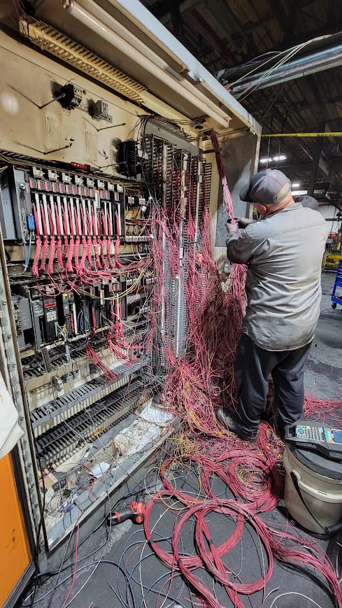 Think-PLC technician rewiring a legacy control panel on a customer plant floor