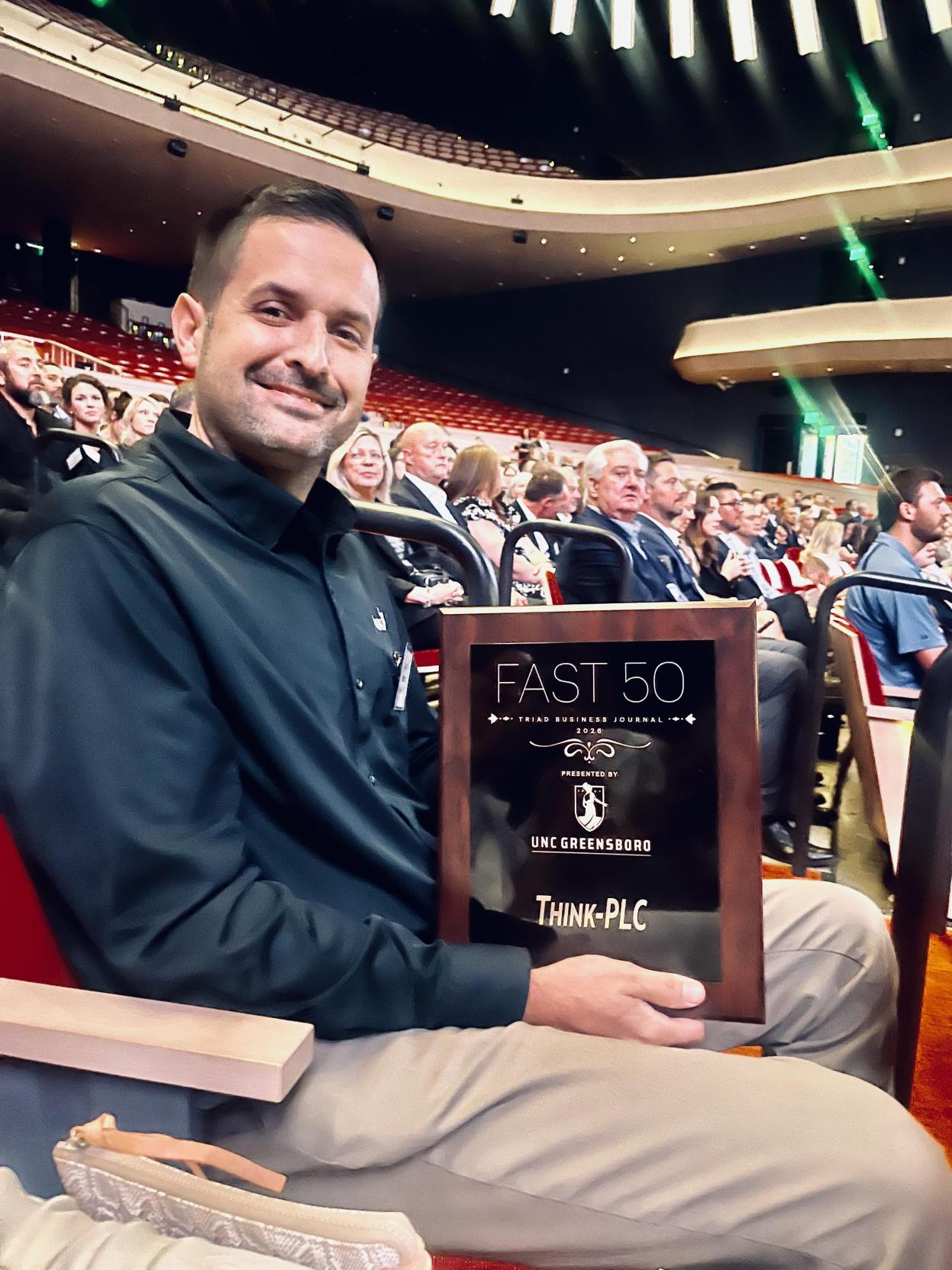 Logan Tedder holding the Fast 50 plaque in the audience